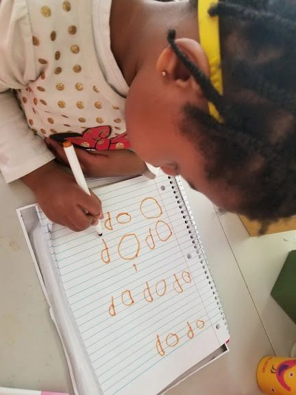 Child practicing writing letters with guidance at Home4Kidz